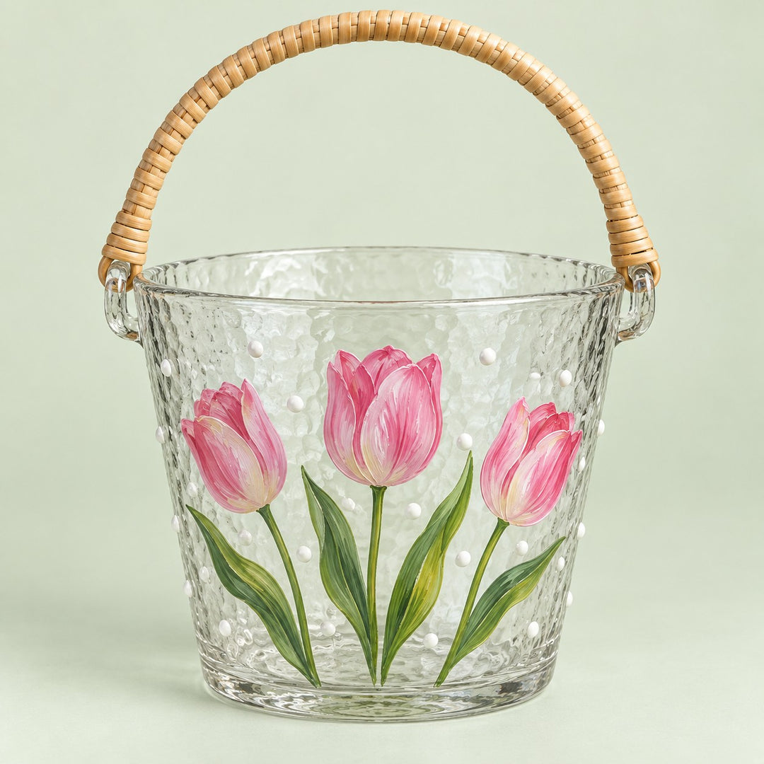 Tulip floral hammered glass ice bucket with woven handle on a pale green backdrop.
