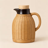 Tan Weave, White Liner thermos shown upright with its cork stopper and rope handle.