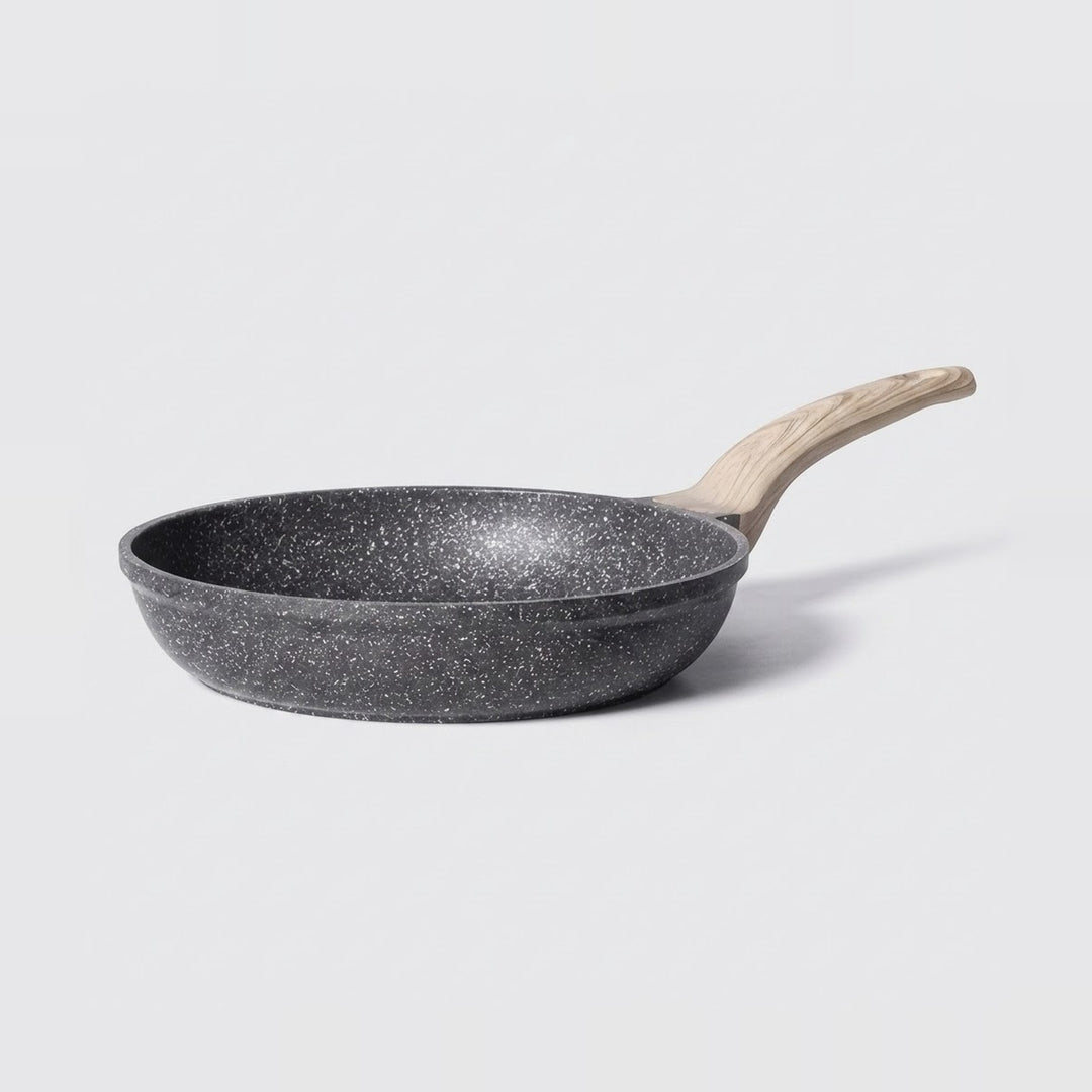 A dark gray non-stick frying pan with a light natural wood handle, shown from a side angle on a light gray background.