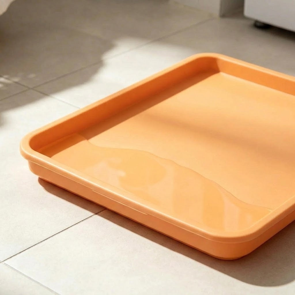 An orange rectangular plastic tray with raised edges, shown on a light beige tiled floor with soft natural shadows.
