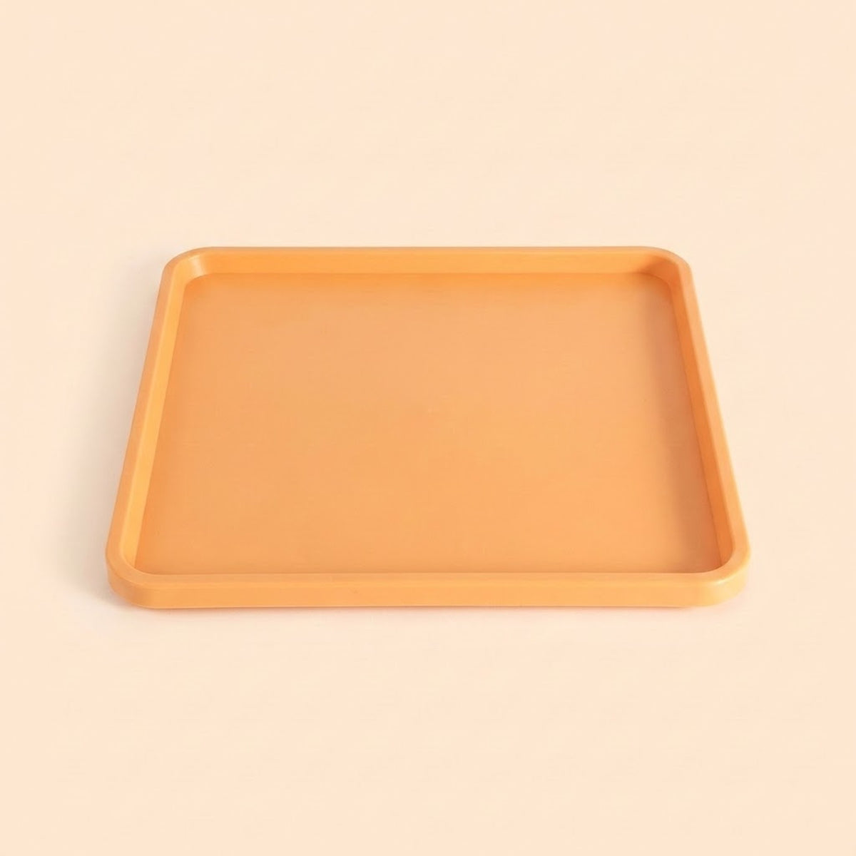A square orange tray with rounded corners and a smooth matte finish, photographed from a top-down perspective on a solid, warm off-white background.