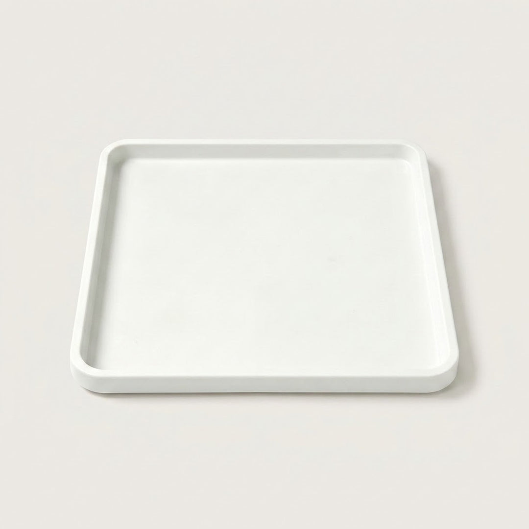 A minimalist square white tray with a slightly raised rim, photographed from a top-down angle on a light beige background.