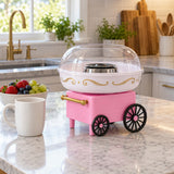 Pink cotton candy maker on a kitchen island beside a mug and fruit bowl to show its countertop scale.