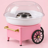 Pink cotton candy maker centered on a soft blush studio backdrop, showing its bowl, dome, wheels, and handle.