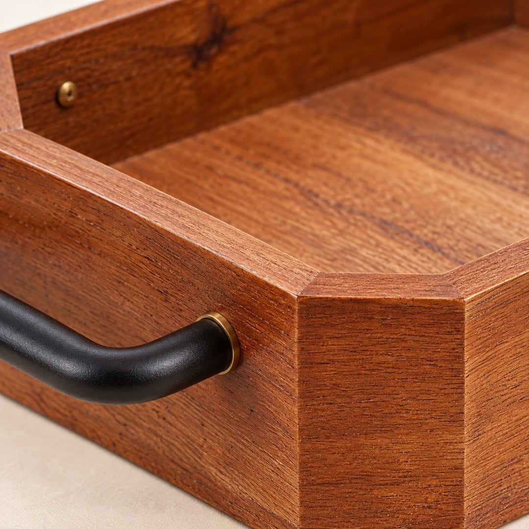 Close view of the wooden serving tray's smooth coffee-brown grain, clipped corner and iron handle.