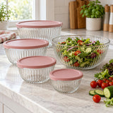 Glass mixing bowls with lids keep salad prep tidy on a bright kitchen counter.