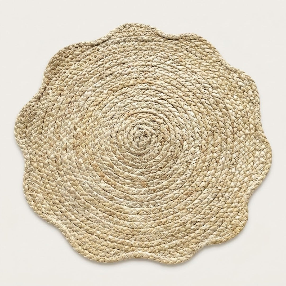 A round natural jute placemat with a scalloped edge, photographed from directly above on a light beige background.
