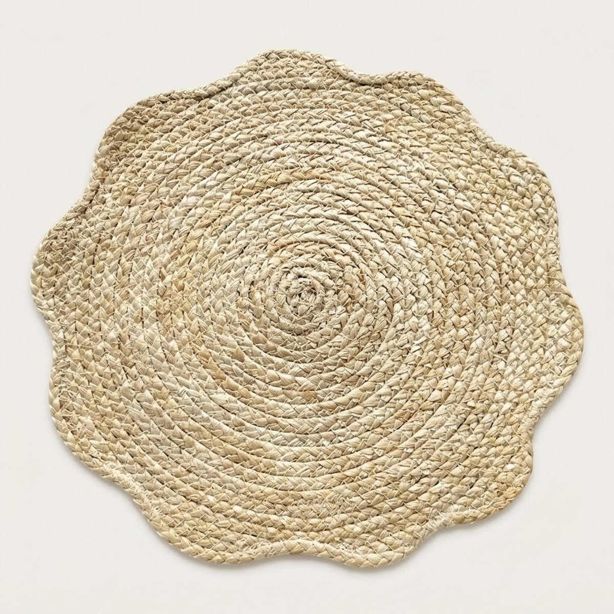 A round natural jute placemat with a scalloped edge, photographed from directly above on a light beige background.
