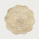 A round braided seagrass placemat with a scalloped edge, shown flat against a light gray background.