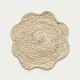 A round woven seagrass placemat with a scalloped edge, shown from a top-down view on a light off-white background.