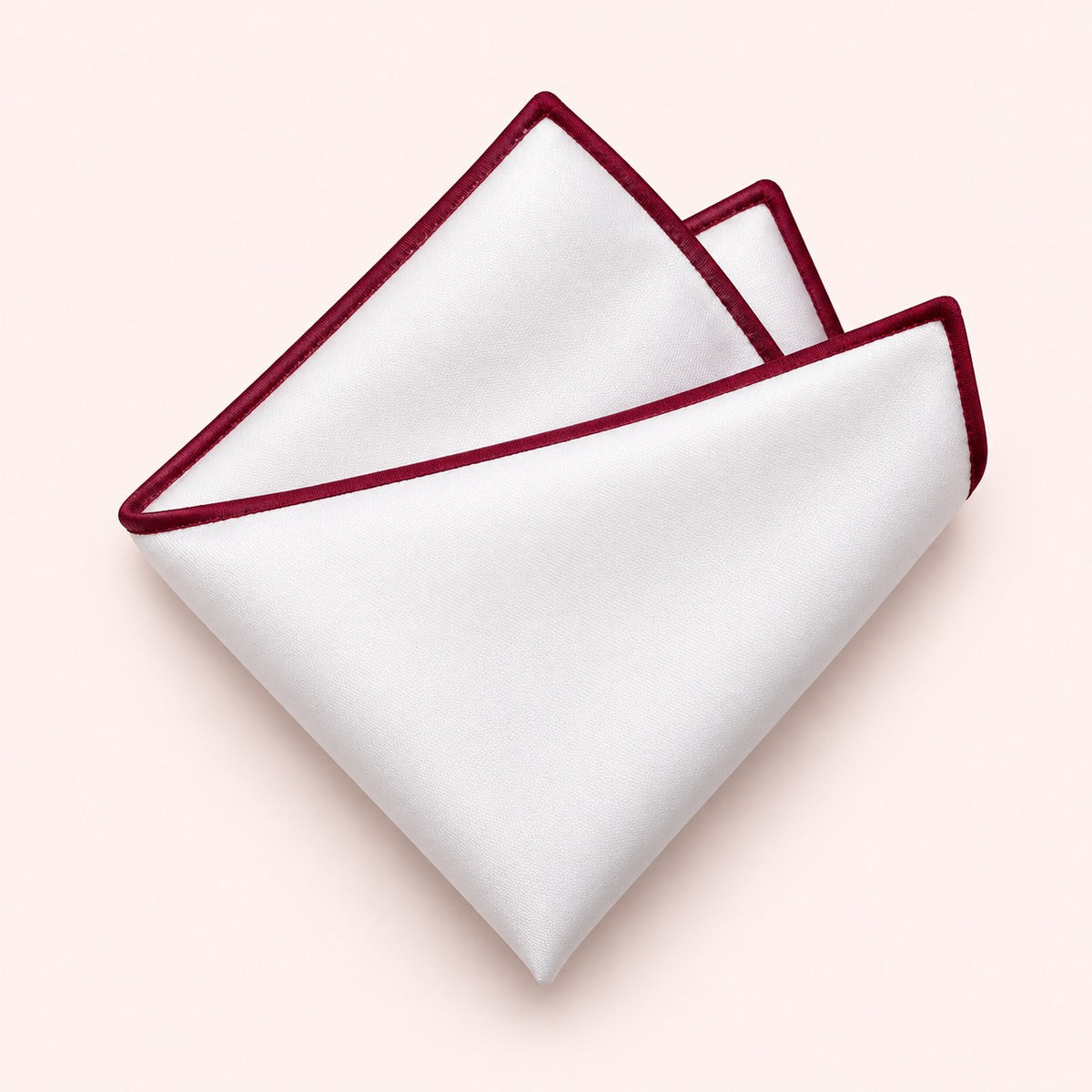 One white polyester pocket square with a burgundy border is folded on a pale blush background.