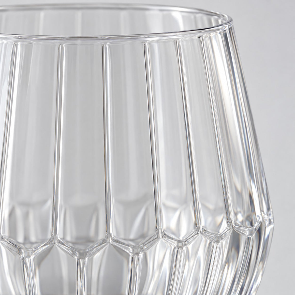 Macro detail shows the clear PET material, vertical ribs and faceted base of the wine glass.