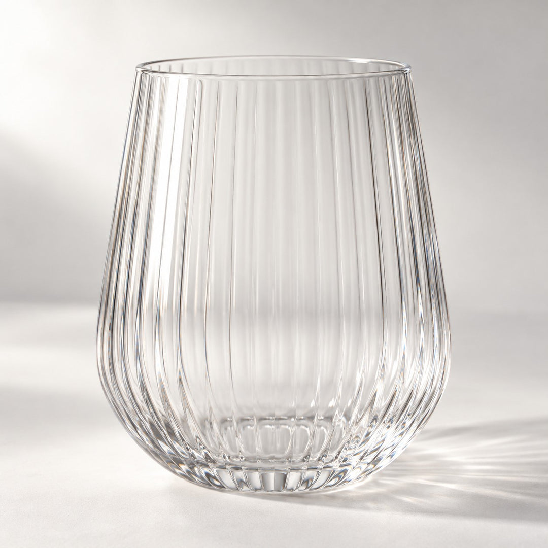 Clear ribbed stemless plastic wine glass highlights its textured sides on a bright studio backdrop.