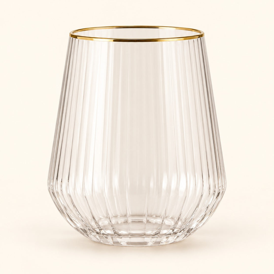 Single gold-rim stemless ribbed plastic wine glass centered on a soft champagne backdrop.