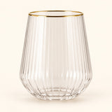 Single gold-rim stemless ribbed plastic wine glass centered on a soft champagne backdrop.
