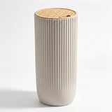 A modern cylindrical pedestal table or planter with a fluted beige ceramic body and a natural woven rattan top, shown on a clean white background.