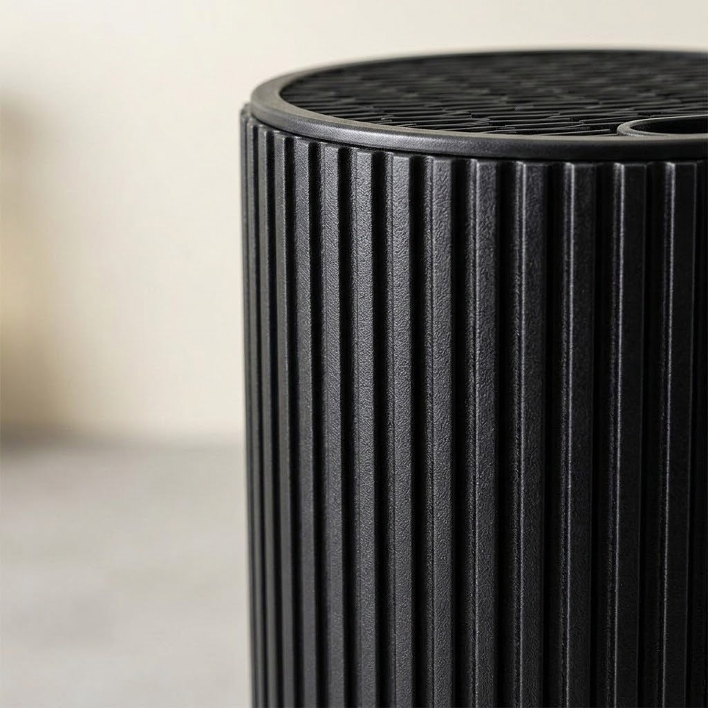 Close-up of a black ribbed cylindrical product, showing a slotted top surface against a softly blurred light background.