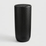 A black cylindrical container with a vertically ribbed fluted texture and a matching ribbed lid, shown on a clean light gray background.