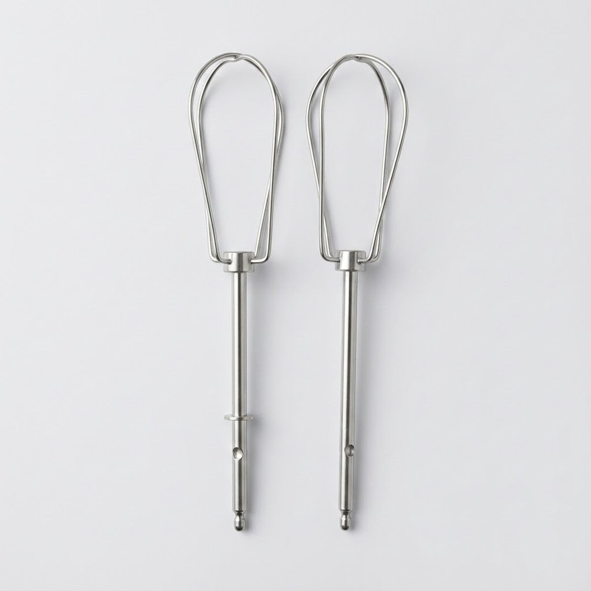 Two silver metal whisk attachments for mixing or whipping, shown side by side on a light gray background.