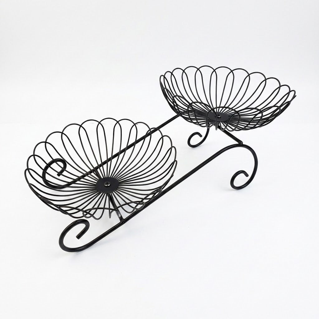 Black metal two-tier wire fruit basket with decorative scrollwork and scalloped bowl edges, shown on a plain white background.