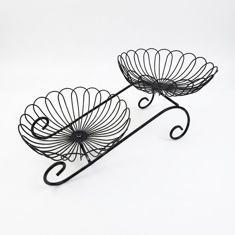 Black metal two-tier wire fruit basket with decorative scrollwork and scalloped bowl edges, shown on a plain white background.