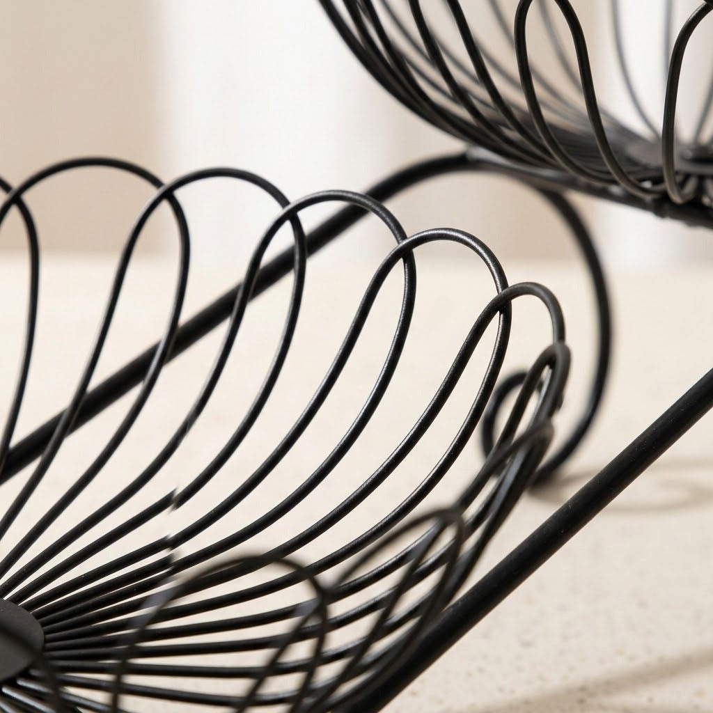 Close-up of a black metal wire spiral rack or basket on a light beige countertop, with part of a matching rack visible in the upper right.