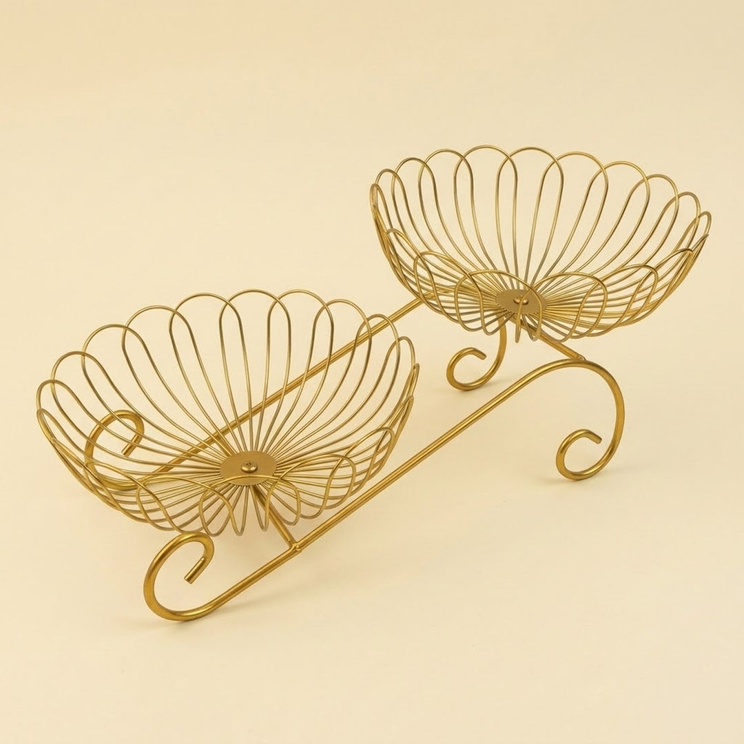 A gold-finished metal wire double-tiered stand with a decorative scroll base, photographed on a solid light beige background.