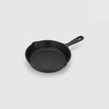 A classic black cast iron skillet with a single loop handle, photographed from a high angle on a light gray background.