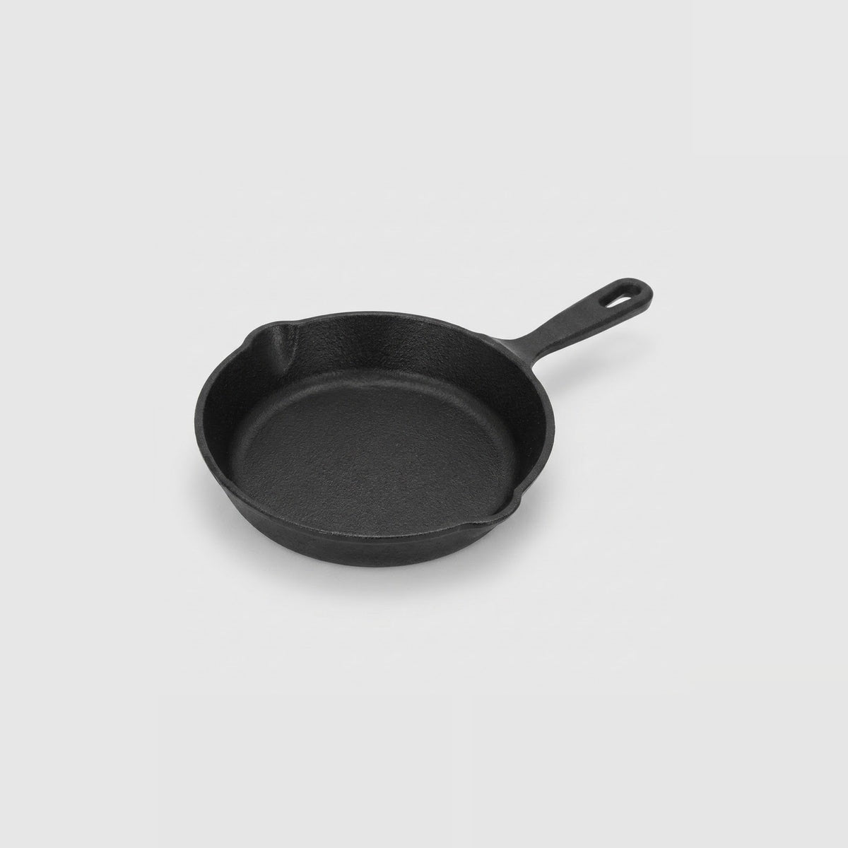 A classic black cast iron skillet with a single loop handle, photographed from a high angle on a light gray background.