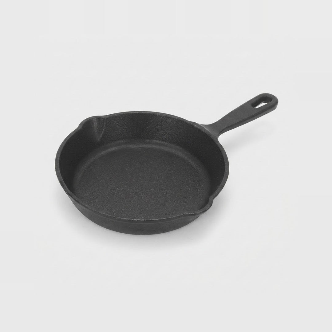 A classic black cast iron skillet with a single loop handle, shown from a high-angle perspective on a light gray background.