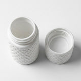 A white textured plastic jar with its threaded lid removed, showing the open jar and separate lid on a clean white background.