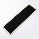 A long rectangular black runner with cream fringe on all sides, photographed on a plain white background.