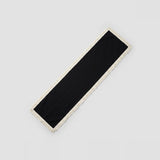 A long rectangular black scarf with a cream-colored fringed border, shown diagonally on a light gray background.