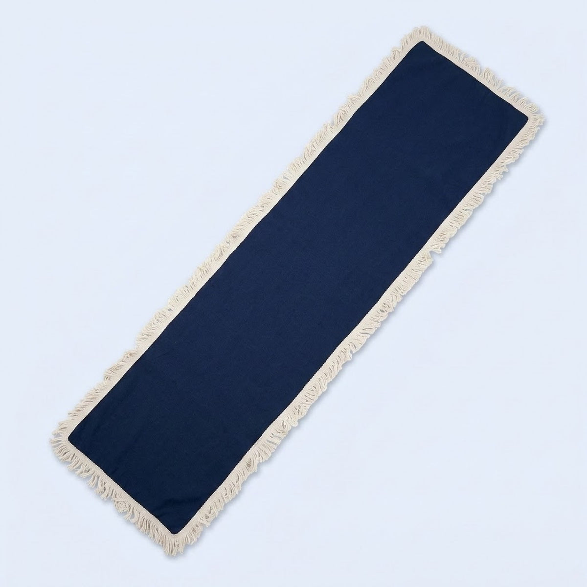 A long rectangular navy blue runner rug with cream-colored fringe on all sides, shown diagonally on a light blue background.