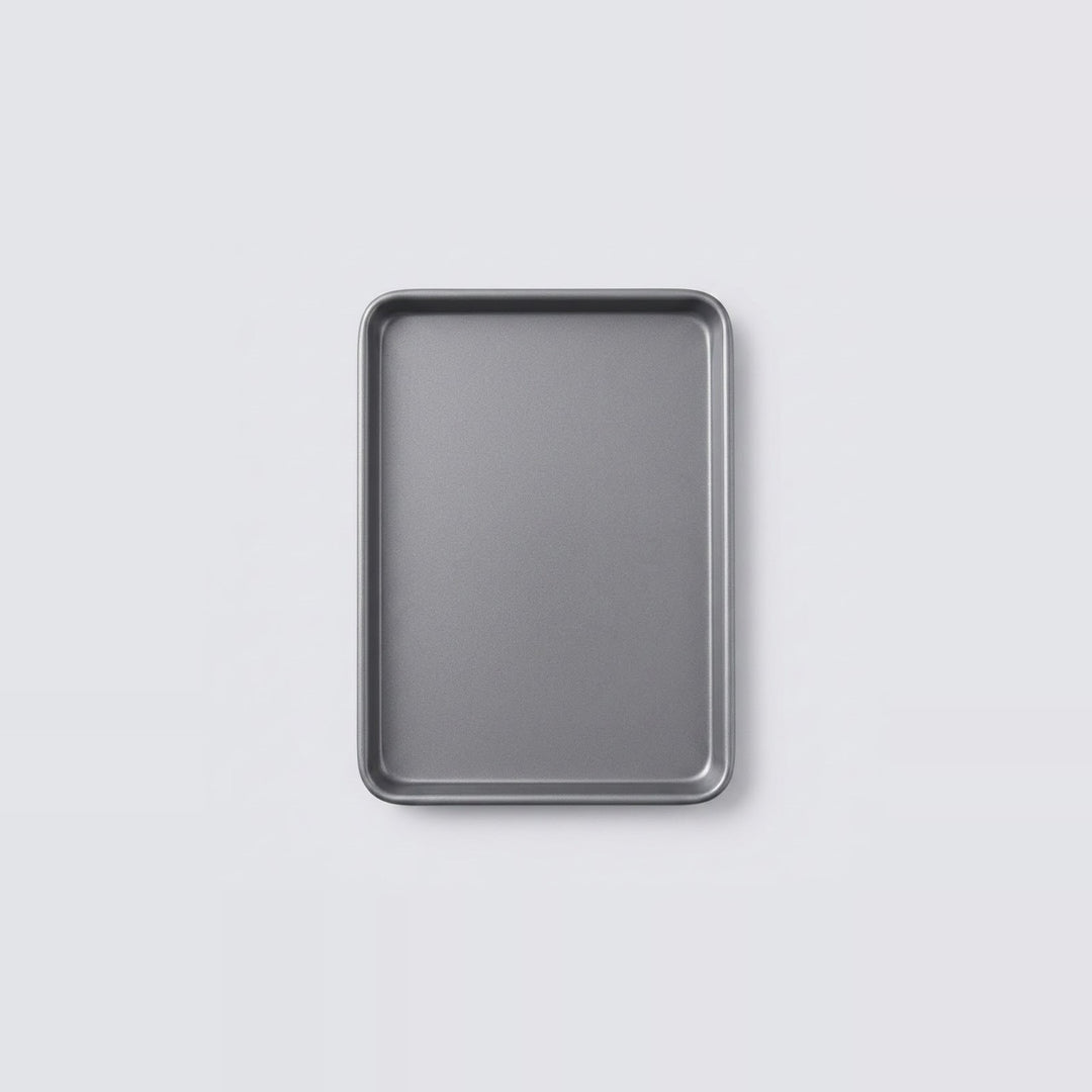 A rectangular metal baking pan with raised edges, shown from above on a light gray background.