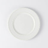 A white ceramic plate with a decorative beaded border, photographed from directly above on a clean white background.