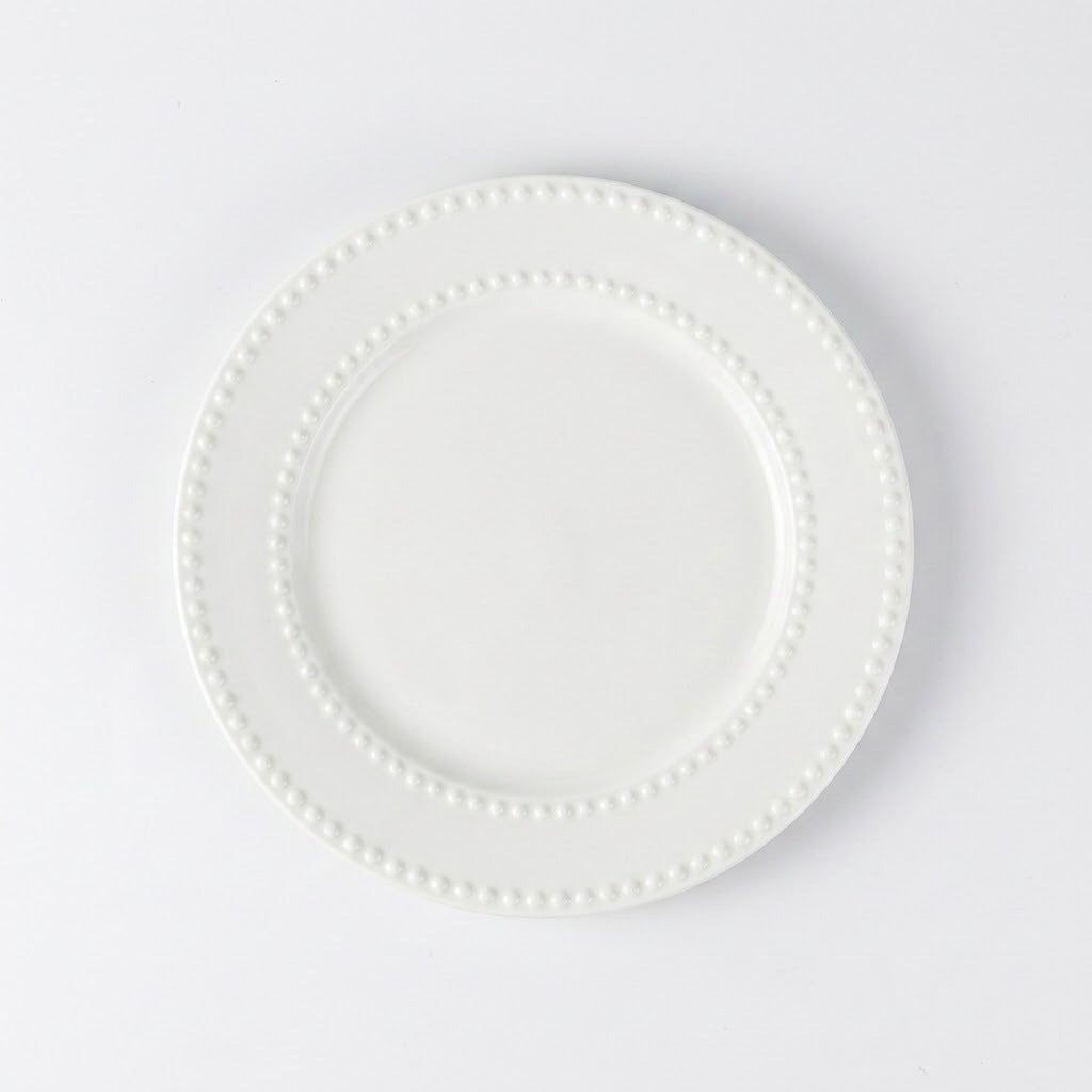 A white ceramic plate with a decorative beaded border, photographed from directly above on a clean white background.