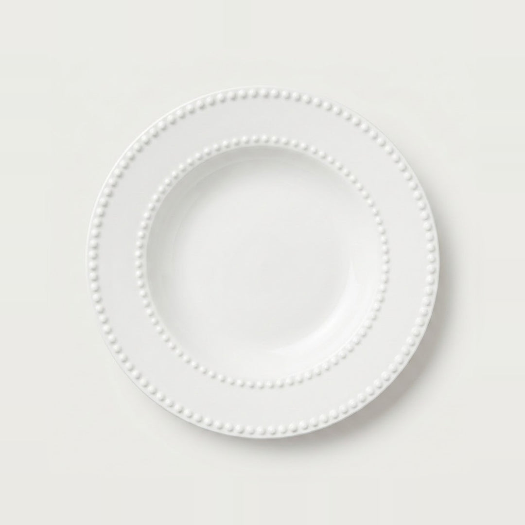 A white ceramic plate with a decorative beaded border, photographed from directly above on a clean, light off-white background.