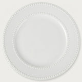 A white ceramic plate with a decorative beaded border, shown from a top-down view on a light off-white background.