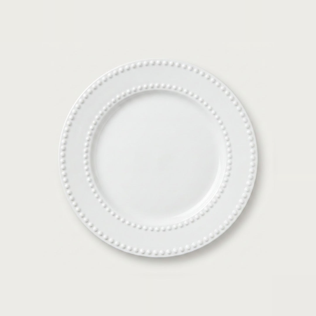 A white ceramic plate with a decorative beaded border, shown from a top-down view on a light gray background.