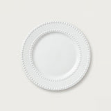 A white ceramic plate with a decorative beaded border, shown from a top-down view on a light gray background.