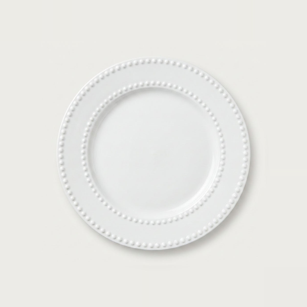 A white ceramic plate with a decorative beaded border, shown from a top-down view on a light gray background.