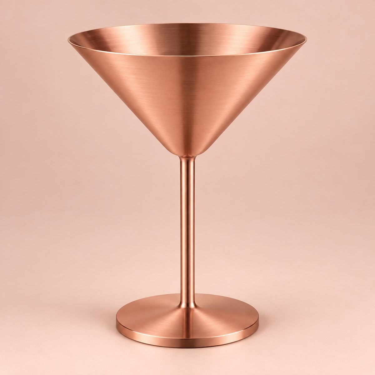 Copper Stainless Steel Martini Cup stands centered against a pale copper blush studio backdrop.