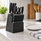 The black kitchen knife set and block sit beside a dinner plate and folded kitchen towel for scale.