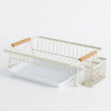 A white metal dish rack set with light wood handles, featuring a main wire drying rack, a matching mesh cup holder, and a white plastic tray on a seamless white background.