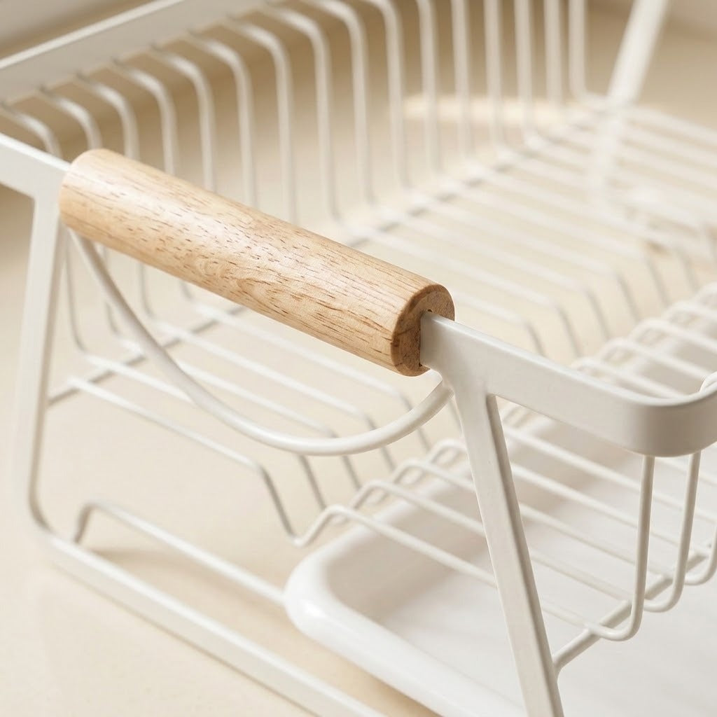 Close-up of a white wire dish rack with a light natural wood handle, set against a warm beige background.