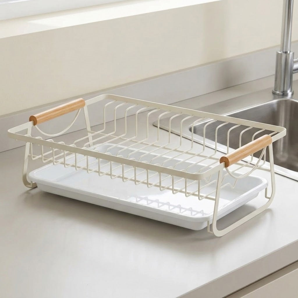 A white wire dish drying rack with light wood handles, shown on a kitchen countertop next to a sink.