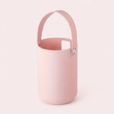A light pink silicone bucket-style cup with a matching pink handle and a small silver snap button, shown on a solid pale pink background.