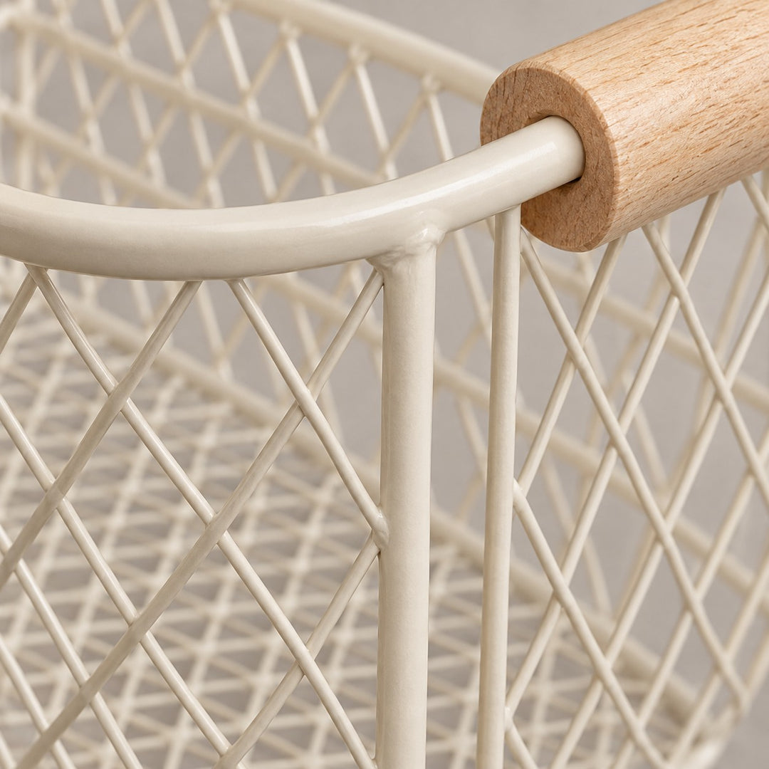 Close-up of the beige wire basket's coated metal mesh, welded joints, and wood grain.