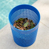 A bright blue plastic cylindrical trash can with a grid-patterned design, filled with dry brown leaves, set on a light stone surface next to a swimming pool.